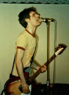 a man singing into a microphone while holding a guitar