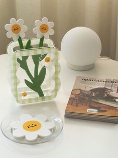 a white table topped with a vase filled with flowers next to a book and an egg