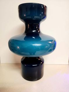 a large blue vase sitting on top of a table next to a white wall and floor