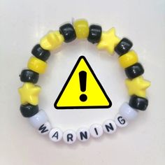 a yellow and black warning sign is on a bracelet with white letters that spell out the word warning