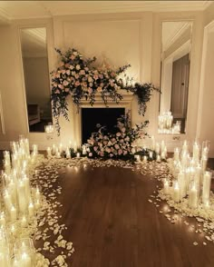 a room filled with lots of candles and flowers on the floor next to a fire place