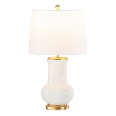 a table lamp with a white shade on top of it and gold trimming around the base