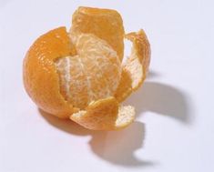 an orange that has been peeled and is sitting on a white surface with the peel still attached