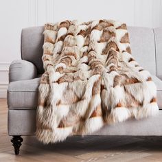 a gray couch with a brown and white fur blanket on it