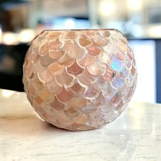 a glass vase sitting on top of a counter next to a wall with lights in the background