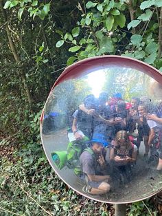 a group of people standing in front of a mirror on the side of a road