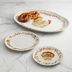 three plates with turkey designs on them sitting on a marble countertop next to each other