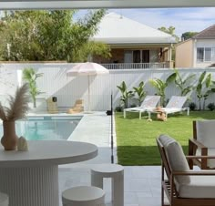 an outdoor patio with chairs and tables next to a swimming pool in front of a house