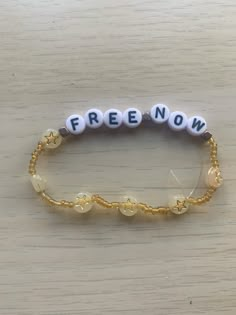 a beaded bracelet with the word free now written in white and gold beads on it