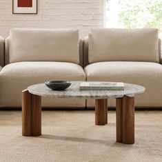 a living room with a couch, coffee table and book on the floor in front of it