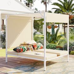 a white canopy bed sitting on top of a wooden floor next to a lush green park