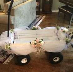 a white wagon decorated with flowers and tulle is sitting on the floor in front of a couch