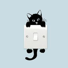 a black cat is sitting on top of a light switch cover with its paws hanging down