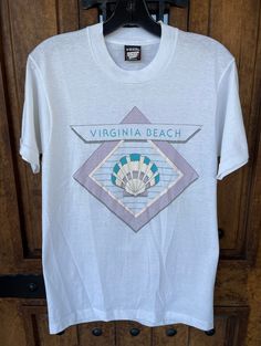 Vintage 80s Virginia Beach Seashell Graphic T-shirt 1980s Tourist Travel Souvenir White Pastel Medium Unisex Beach Tee - Etsy Vintage Graphic Print Beach T-shirt, Vintage Graphic Print T-shirt For Beach, Vintage Pre-shrunk T-shirt For Beach, Vintage White Tops For Beach Season, White Vintage Tops For Beach Season, Vintage Screen Print T-shirt For Beach Season, Vintage Graphic Print T-shirt For Beach Season, Vintage T-shirt For Beach Vacation, Vintage Cotton T-shirt For Beach