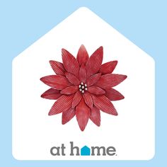 a red flower sitting on top of a blue and white house with the words at home above it