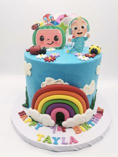 a birthday cake decorated with cartoon characters and rainbows