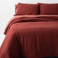 a bed with red sheets and pillows on it