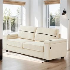 a white couch sitting on top of a hard wood floor next to a large window