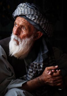 an old man with a long white beard wearing a striped hat and holding his hands together