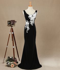 a black and white evening gown on display next to a tripod with a camera