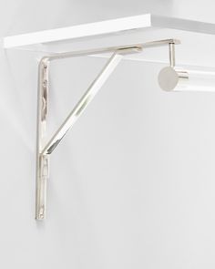 a white wall mounted shelf with a light on it's side and a round object hanging from the ceiling