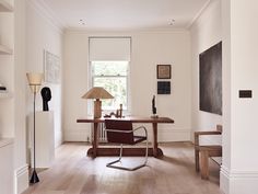 a living room filled with furniture and a lamp on top of a wooden table in front of a window