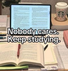 an open laptop computer sitting on top of a desk next to books and coffee cup