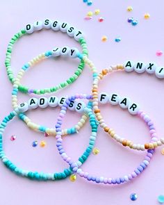 four bracelets with words written on them and confetti scattered around the beads