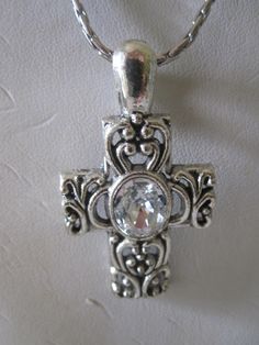 Beautiful reminder of our Christian faith especially needed in trying times. Designed with lovely silver scroll work and a large white rhinestone in the center. Cross measures 1.75 inch by 1 inch and can be easily removed to snap on any chain you choose . The chain is stainless steel and measures 18 inches.   In excellent vintage condition! Comes in a gift box and gift bag. Silver Cross Jewelry, Vero Beach Fl, Scroll Work, Rhinestone Cross, Vero Beach, White Rhinestone, Cross Jewelry, Silver Cross, Christian Faith