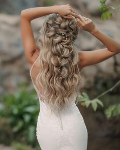 a woman with long blonde hair wearing a wedding dress and holding her hands behind her head