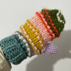 there is a hand that has some knitted items on it