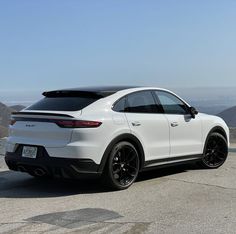 a white porsche cayenne parked on top of a mountain