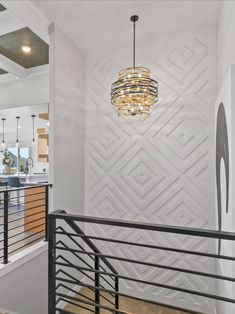 a chandelier hanging from the ceiling in a room with white walls and wood floors