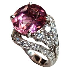 This cocktail ring has an asymmetric geometry that contrasts a beautiful pink Tourmaline on one side, with a vibrant and bright tone, oval cut ct 7.38 (from Nigeria) on the other side diamonds. The double shank structure is also completely set with brilliant-cut diamonds. The overall carat of the diamonds (color E/F clarity Vs) is 2.21ct. The name of this creation is HANAMI and takes its cue from the Japanese cherry blossom, which has bright pink petals. The stem design is meant to recall classic Japanese garden jumpers with their ticular curved lines. The whole ring is made of 18kt white gold Luxury Pink Oval Sapphire Ring, Elegant Pink Multi-stone Sapphire Ring, Luxury Pink Oval Diamond Ring, Pink Oval Multi-stone Ruby Ring, Formal Pink Multi-stone Sapphire Ring, Dazzling Pink Oval Diamond Ring, Pink Oval Diamond Ring With Dazzling Style, Formal Oval Pink Sapphire Ring, Pink Oval Ruby Ring With Gemstone Accents