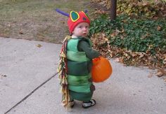 a little boy dressed up as the very hungry caterpillar with a pumpkin in his hand