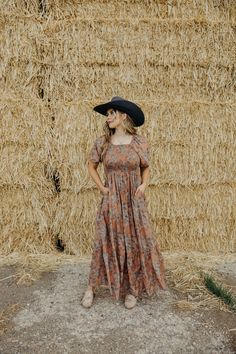 Unleash your inner free spirit with the Indigo Dress! With a flattering square neckline, smocked bodice, and puff sleeves, this midi dress exudes bohemian vibes. The tiered skirt and vibrant floral print add a touch of Western flair. Perfect for making a statement at any event! Courtney is wearing size small paired with the Felt Cowboy ProHat and The Adaire Mules Bohemian Smocked Puff Sleeve Dress, Bohemian Dress With Smocked Back And Puff Sleeves, Bohemian Smocked Dress With Puff Sleeves, Bohemian Maxi Dress With Puff Sleeves And Smocked Back, Bohemian Fitted Smocked Dress With Puff Sleeves, Fitted Bohemian Smocked Dress With Puff Sleeves, Bohemian Brown Tiered Maxi Dress, Billowy Bohemian Tiered Dress, Bohemian Tiered Skirt Midi Dress For Garden Party