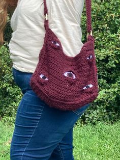 a woman carrying a crocheted purse with eyes on it