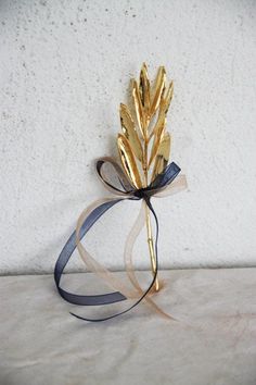 a gold flower with a ribbon tied around it sitting on a table next to a white wall