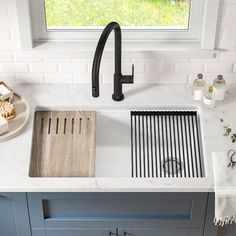 a white kitchen sink sitting under a window next to a faucet and counter top