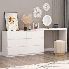 a white dresser sitting in a living room next to a window with pictures on it