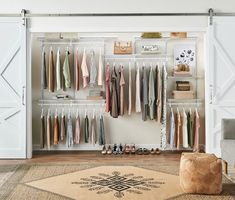 an organized closet with clothes hanging on the wall and a rug in front of it