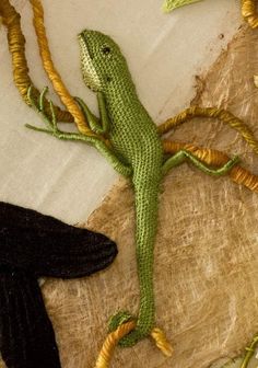 a green lizard sitting on top of a piece of cloth next to a black bird