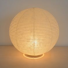 a white lamp sitting on top of a wooden table next to a light bulb in the shape of a ball