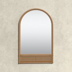 an arched mirror on the wall with a wooden frame and rattan trim around it