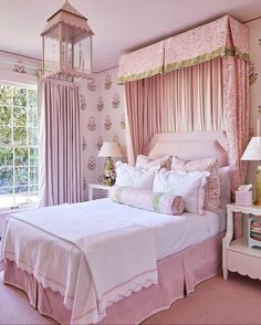 a bedroom with pink walls and curtains on the windowsills, a bed in between two nightstands