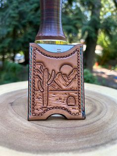 a leather bottle holder with a desert scene on the front, and a cactus in the back