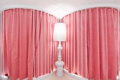 a room with pink curtains and a white lamp