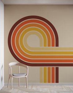 a chair sitting in front of a wall with an orange and yellow design on it