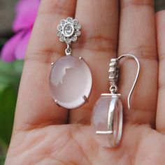 "Subtle oval shaped cabochon rose quartz, dangling from an oval diamond flower, set in 14k white gold, these stunners make for those perfect and unique wedding earrings. An exclusive piece from our shop, these earrings are absolutely to die for..! Oval Diamond - Dangle Earrings - 14K Gold - Rose Quartz - Wedding Earrings - Gemstone Bridal Earrings * Gemstone 1 : Natural Diamonds. * Diamond Wt. : 0.37 Cts (Oval Cut) + 0.25 cts (Round) * Color-Clarity Grade : G Color, Vs Purity * Gemstone 2 : Natu Elegant Rose Quartz Jewelry For Formal Occasions, Elegant Rose Quartz Wedding Jewelry, Elegant Silver Rose Quartz Jewelry, Elegant Silver Oval Cabochon Earrings, Elegant Oval Cabochon Sterling Silver Earrings, Elegant Sterling Silver Oval Cabochon Earrings, Formal White Flower-shaped Diamond Earrings, Elegant Flower-shaped Earrings With Sparkling Stones, Elegant Silver Rose Quartz Earrings