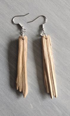 two pieces of wood are hanging from silver earwires on a gray table top